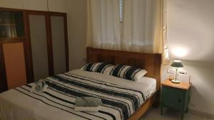 Gil's Home of Joy & Serenity في حيفا: غرفة نوم بسرير وطاولة مع مصباح