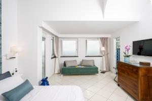 a bedroom with a bed and a couch and a tv at La Divina Amalfi Coast in Praiano