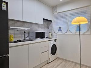 una cucina con lavatrice e lampada gialla di Iceblue stay a Seul