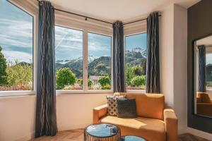a living room with a couch and large windows at Villa Sonnenhof Boutique-Hotel in Bad Reichenhall
