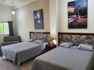 a bedroom with two beds and a chair at Coconut village in El Zapote