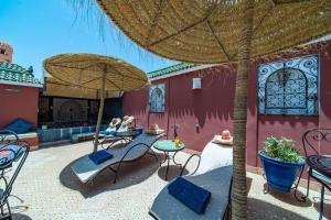 une terrasse avec des chaises, des tables et un parasol dans l'établissement Riad Khadoj-Marrakech-Traditional, à Marrakech