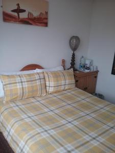 a bed with a plaid bedspread and a surfboard on it at Fairways Guest House in Newquay