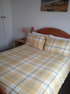 a bed with a plaid comforter and two pillows at Fairways Guest House in Newquay