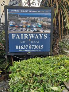 una señal para una casa de huéspedes de las calles junto a algunos arbustos en Fairways Guest House, en Newquay