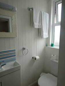 Baño blanco con aseo y lavamanos en Fairways Guest House, en Newquay