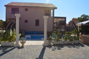 a patio with pillars and potted plants in front of a house at Kuća NIKA in Tribunj