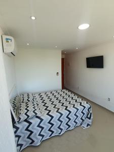 een slaapkamer met een bed in een witte kamer bij Suítes Do Forno in Arraial do Cabo