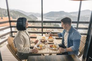 a man and woman sitting at a table eating food at Villa Montana Zaovine in Bajina Bašta