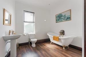 a bathroom with a tub and a toilet and a sink at Logan Lodge, Great Yarmouth - for your large group! in Great Yarmouth +29 photos