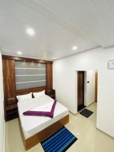 ein Schlafzimmer mit einem Bett mit einem lila Handtuch darauf in der Unterkunft Drizzle Valley Cottage in Munnar