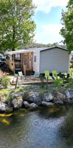レージュ・キャップ・フェレにあるMobil home tout confort Camping Les VIVIERS CAP FERRETの水の横に緑の椅子を置いた家