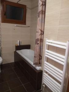 y baño con bañera y cortina de ducha. en Family friendly house nearby the sea, en Agia Paraskevi
