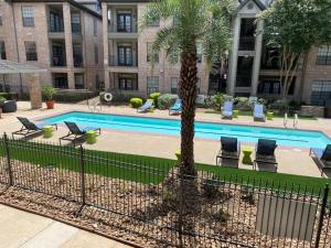 a pool with chairs and a palm tree in front of a building at Central Houston- Urban Living in Houston