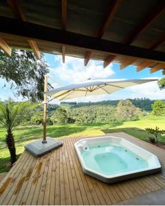 uma banheira de hidromassagem sentada num deque com um guarda-sol em Casa com vista para as montanhas em Atibaia
