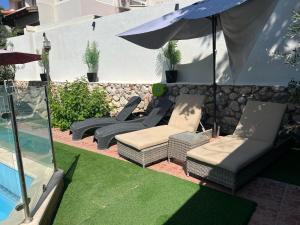 d'une terrasse avec des chaises, un parasol et de la pelouse. dans l'établissement אחוזת רוממה - Villa Romema, à Safed