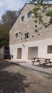 a picnic table in front of a stone building at Un Petit Coin Douillet au Pradel in Montredon-Labessonnié