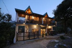 ein Haus mit einem Balkon und einem Auto davor in der Unterkunft Goroomgo Wooden Umbrella Bhimtal - Natural landscape Mountain View in Bhīm Tāl