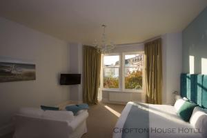 a bedroom with a bed and a couch and a window at Crofton House Hotel in Torquay