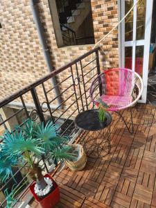 einen Balkon mit einem Stuhl, einem Tisch und Topfpflanzen in der Unterkunft Elyam's Home 2 in Douala