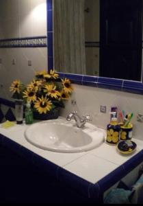 un lavabo con espejo y flores. en Habitación en chalet cerca de la playa en Benicasim, en Benicàssim