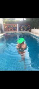 una persona en una piscina con sombrero verde en Habitación en chalet cerca de la playa en Benicasim, en Benicàssim