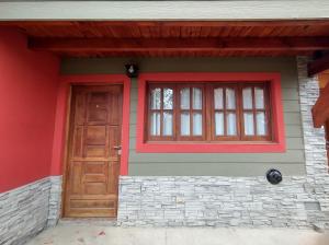 a house with a red door and a window at Cabañas Buena Vista Rosi in San Carlos de Bariloche
