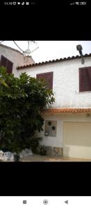 a white house with red windows and a tree at Habitación en chalet cerca de la playa en Benicasim in Benicàssim