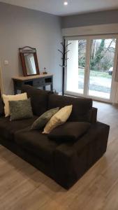 a black couch with pillows in a living room at Un Petit Coin Douillet au Pradel in Montredon-Labessonnié