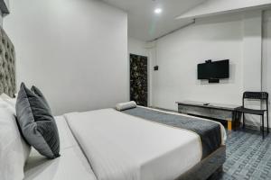 a bedroom with a bed and a desk and a television at HOTEL BB HOUSE in Mumbai