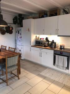 cocina con armarios blancos, mesa y microondas en Køge Bed & Kitchen, en Køge