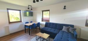 Beskidzki Zakątek Ustroń في أوسترون: غرفة معيشة مع أريكة زرقاء وطاولة