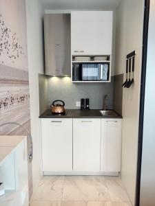 a kitchen with white cabinets and a microwave at Bed & Breakfast Slaperduin in Buren