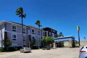 um edifício com palmeiras e carros estacionados num parque de estacionamento em Comfort Inn & Suites Donna near I-2 em Donna