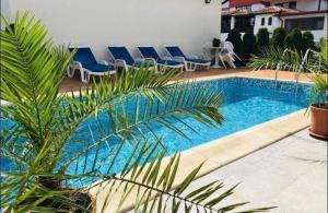 a swimming pool with blue chairs next to a building at Апартамент за гости ДЕНИЦА in Obzor