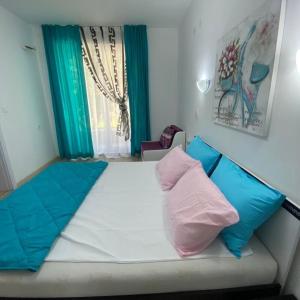 a bed with blue and pink pillows in a room at Апартамент за гости ДЕНИЦА in Obzor +9 photos