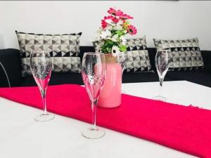 a table with three wine glasses and a vase with flowers at Апартамент за гости ДЕНИЦА in Obzor