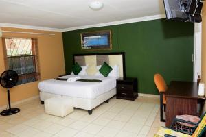a bedroom with a bed and a green wall at Obasi Green Inn Guesthouse in Roodepoort