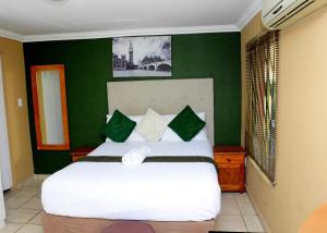 a bedroom with a large white bed with green walls at Obasi Green Inn Guesthouse in Roodepoort
