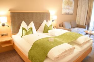 a bedroom with a large bed with green and white pillows at Gartenhotel Kloepferkeller in Eibiswald