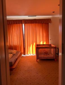 a bedroom with a bed and a window with orange curtains at Apartman De Lux in Nyíregyháza