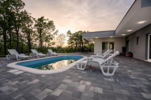 a patio with white chairs and a swimming pool at New Villa Nadalina in Lovreć