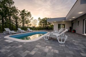 eine Terrasse mit weißen Stühlen und einem Pool in der Unterkunft Villa Nadalina, Cista Provo in Lovreć