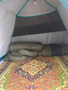 a bed in a tent with a rug on it at GarhKumoan in Kedārnāth