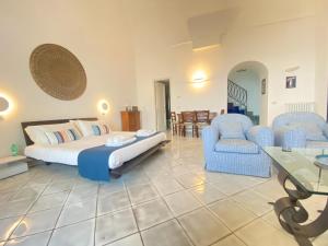 a bedroom with a bed and two chairs and a table at Suite Palazzo Capri - Seaview in Capri