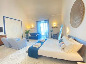 a large bedroom with a large bed and blue chairs at Suite Palazzo Capri - Seaview in Capri