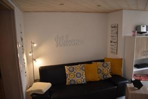 ein Wohnzimmer mit einem schwarzen Sofa und gelben Kissen in der Unterkunft Seniorenfreundliche und behindertengerechte Erdgeschosswohnung mit hohem Komfort für drei Personen in Bad Brambach