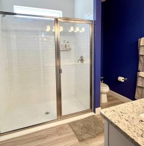 a glass shower in a bathroom with blue walls at The Arcade close to downtown with fenced yard in Sanford
