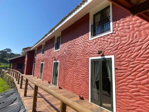 un edificio rojo con una terraza de madera al lado en Fazenda com 2 casas independentes - 10 suítes com PISCINA ou 4 suítes com JACUZZI - Churrasqueira Wi-Fi 400MB Lagos Cavalos e indicação Cozinheira, en Pedra Bela