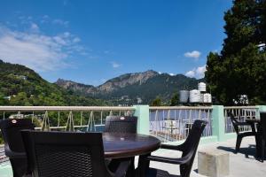een tafel en stoelen op een balkon met uitzicht op de bergen bij Spruce Hill Hotel & Restro in Nainital